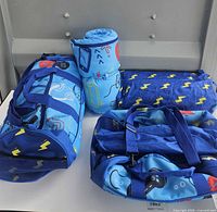 Two duffle bags, one rolled sleeping bag and one folded tent bag displayed