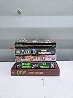 Front view of stacked five paperback books showing spines with titles and authors