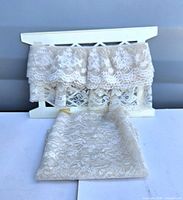 Long lace trim draped on white holder with folded remnant in foreground