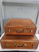Stacked view of both brown hard sided suitcases closed