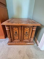 Front view of one walnut veneer end table showing doors, molding and turned columns