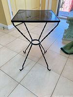 Full view of square glass accent table on wrought iron base