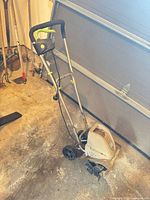 Full view of Earthwise corded electric tiller with handle, housing, wheels and cord retainer visible