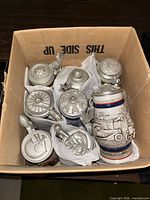 Box containing multiple ceramic beer steins with pewter lids