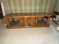 Front view of coffee table showing overall form, turned column legs and central cabinet doors