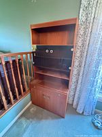 Front view of full bookcase showing upper open shelf, glass-front middle section, central open shelf and lower cabinet