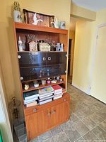 Front view of tall wood veneer hutch with glass sliding doors, open shelves, drawers and lower cabinet