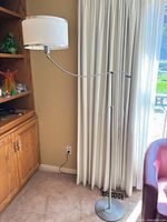 Full view of brushed nickel floor lamp with white drum shade