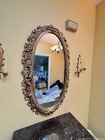 Full view of ornate gold oval mirror on wall showing size and style