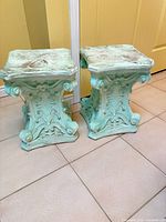 Front view of both ornate plaster pedestal stands