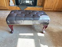 Full view of ottoman showing upholstery, nailhead trim and cabriole legs