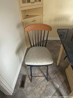 Full view of one stool showing wood backrest, metal slats, upholstered seat