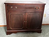 Front view of wood buffet sideboard showing drawer, doors, hardware, and feet