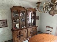 Full view of wooden hutch beside dining table showing upper glass display and lower storage