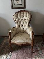 Front view of tufted gentleman’s chair showing carved frame and upholstery
