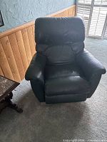 Front view of first recliner showing leather upholstery and padded armrests