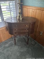 Front and side view of wood sewing cabinet showing three drawers and turned legs