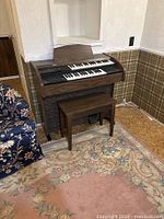 Front view of organ with bench showing keys, control panel, speaker grille