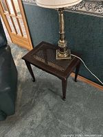 Wooden end table with cane lattice top and lamp placed on it