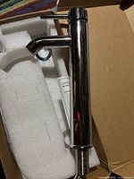Chrome faucet lying in foam in box, side handle visible