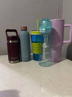 Five assorted bottles and handled tumblers standing side by side