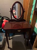 Full view of wooden vanity with oval mirror