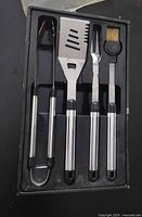 Four stainless steel BBQ tools in tray
