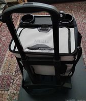 Front view showing telescoping handle, white lid, cup holders and cart frame