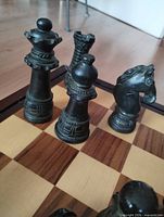Close view of dark green/black carved chess pieces on board