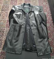 Front view of dark brown Danier leather coat laid flat, buttons fastened