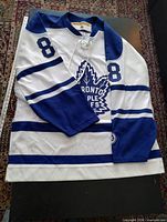Front of white and blue Maple Leafs jersey showing number 8 on sleeve and crest