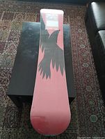 Top view of the snowboard showing topsheet graphics and protective wrap