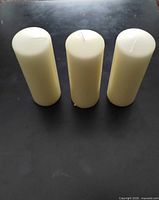 Three cream pillar candles standing upright