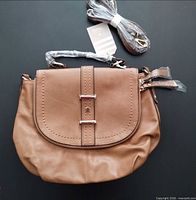 Front view of tan Oasis saddlebag purse with flap and buckle detail, strap wrapped