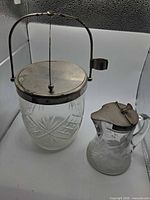 Large cut-glass jar and small etched-glass pitcher side by side