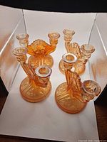 Group view of four matching orange iridescent glass double candlesticks