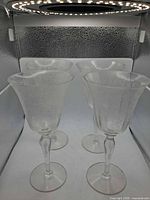 Four clear etched glass goblets standing upright