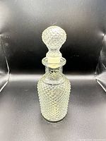 Full view of clear diamond-pattern glass decanter with stopper inserted