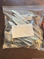 Zip bag labeled “30 Pce Flatware service 4” holding assorted flatware pieces