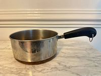 Side profile of saucepan showing stainless body, copper bottom, Bakelite handle