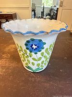 Overall view of white ceramic flower pot with blue and green floral design and scalloped rim