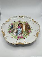 Full view of porcelain plate showing central scene and scalloped gilded rim