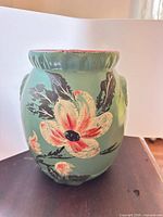 Front view of teal pottery jar showing floral motif