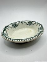 Top angled view of oval ceramic soap dish showing floral pattern and beaded rim