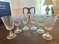 Full set of six clear stemmed glasses on table