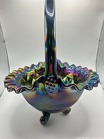 Full view of iridescent ruffled carnival glass basket with handle and tripod feet
