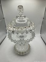 Front view of clear glass pedestal candy dish with lid