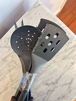 Four black nylon utensil heads taped together