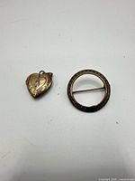 Front view of heart locket and round brooch