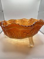 Side view showing marigold iridescent body, ruffled edge, and three clear feet